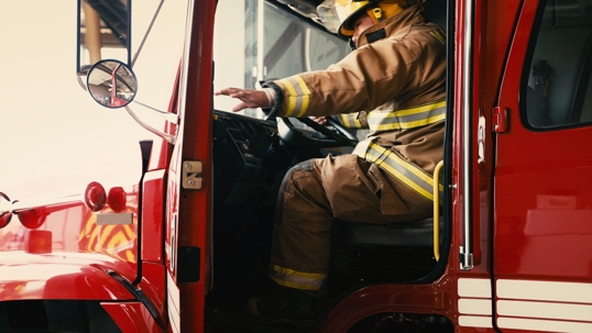 Firefighter reaches to close the door on the engine