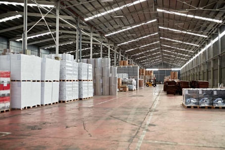 Inside of a brightly-lit warehouse with filled palettes and forklifts